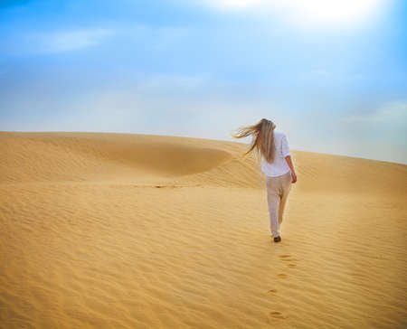 Beauty blond woman walking in desert. Sahara desert - Douz, Tunisia.の写真素材