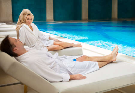 Young couple relaxing by the poolside wearing toweling robesの写真素材
