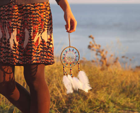 Brunette woman with long hair holding dream catcher in her handsの写真素材