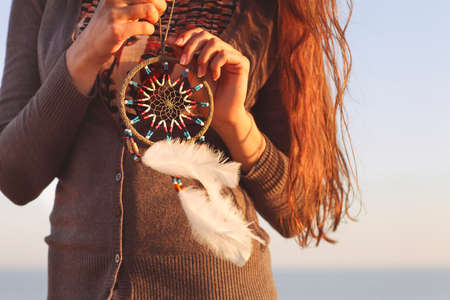 Brunette woman with long hair holding dream catcher in her handsの写真素材