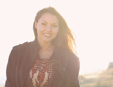 Portrait of the beautiful brunette woman at the windy autumn day relaxing on coast feeling good