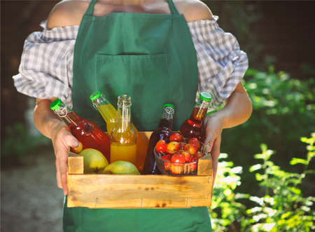Woman holding wooden box with bottles of lemonade - cherry, pear and lemon tasteの写真素材