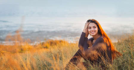 Portrait of the beautiful brunette woman at the windy autumn day relaxing on coast feeling goodの写真素材