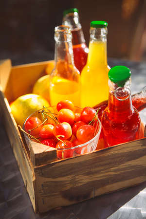 Lemonade with cherry, pear and lemon in the wooden box on the garden picnicの写真素材