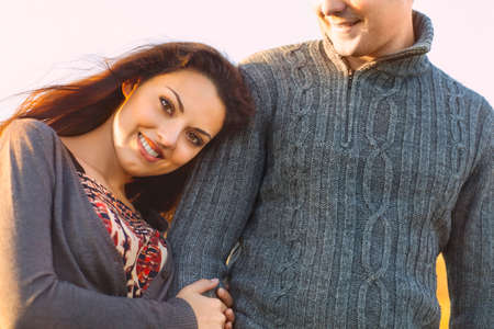 Closeup portrait of young happy couple laughing in a cold day by the autumn seaの写真素材