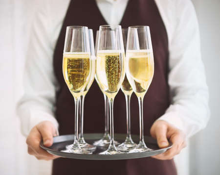 Professional male waiter in uniform serving champagne. DOF. Natural light. Photo in motionの写真素材