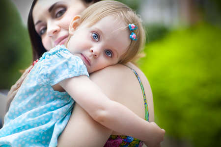 Portrait of a beautiful young mother with daughter in summer park