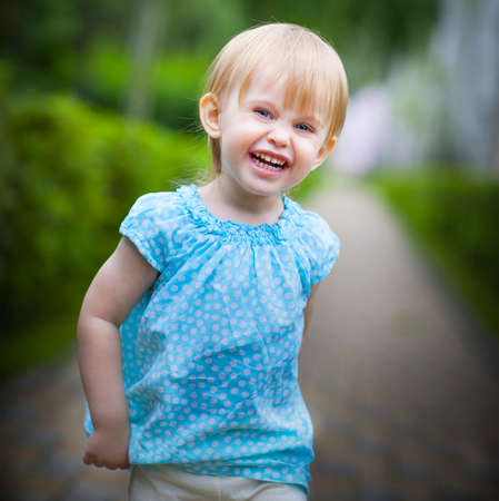 Portrait of a smiling running toddler girl in motion outdoorsの写真素材