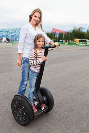 Happy young caucasian woman and her daughter on the segway in the city