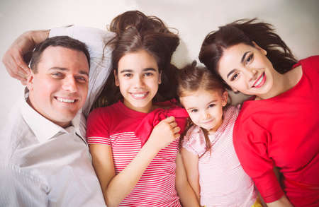 Portrait of a happy young family with kids lying on a floor at homeの写真素材