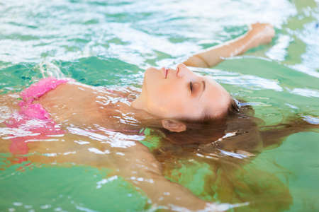 Young blond woman relaxing in the water in the poolの写真素材