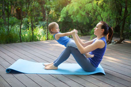 Mother and daughter doing exercise practicing yoga outdoors. Healthy lifestyleの写真素材