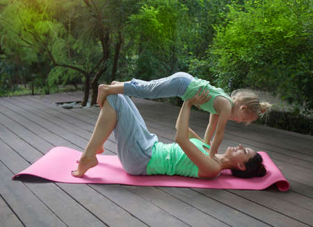 Mother and daughter doing exercise practicing yoga outdoors. Healthy lifestyleの写真素材
