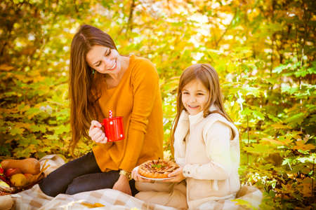 Two cheerful sisters in the park on picnic in warm autumn dayの写真素材