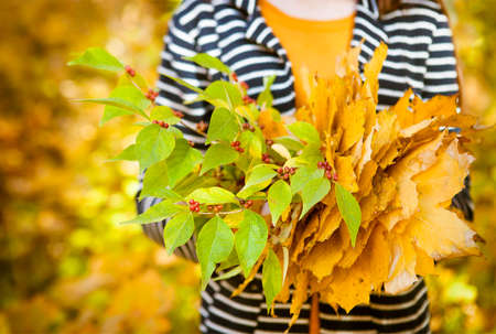 Young girl with leaves in her hands. Autumn october background. Close up