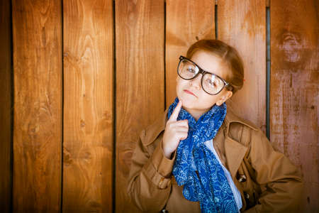 Funny little girl with glasses on wooden wall backgroundの写真素材