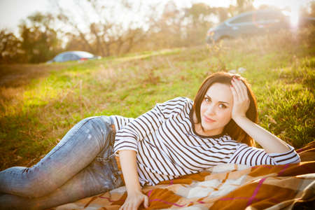 Portrait of a smiling brunette woman relaxing outdoors on picnic in a autumn day