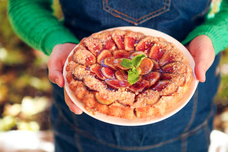 Homemade fig pie with nuts and honey in hands of a womanの写真素材