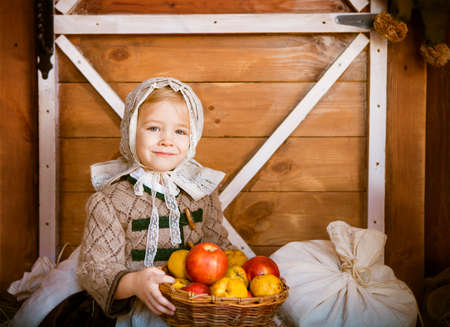 Vintage styled photo of little smiling girl in farm holding basket with applesの写真素材