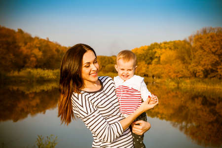 Portrait of smiling mother and baby on autumn lakeの写真素材