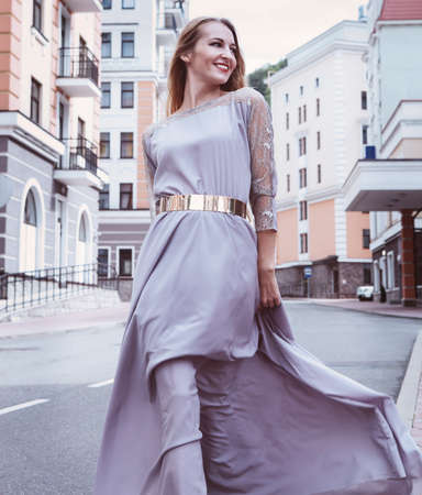 Beautiful blond woman in long dress walking outdoorsの写真素材
