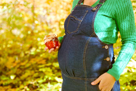 Happy pregnant woman in the autumn forest. Close up on bellyの写真素材