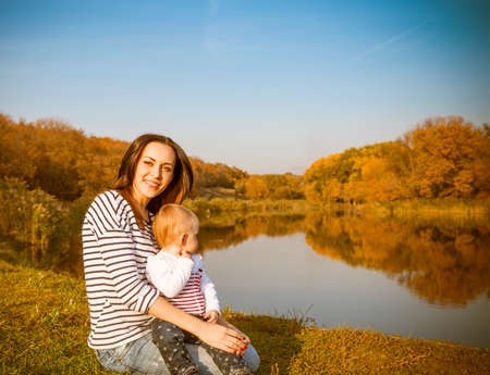 Portrait of smiling mother and baby on autumn lakeの写真素材