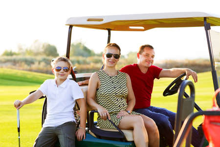 Happy family portrait in a cart at the golf courseの写真素材
