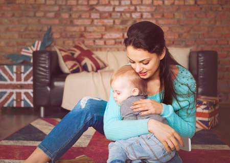 Young mother playing with her baby daughter at homeの写真素材