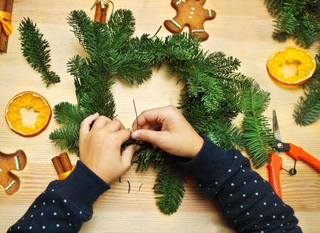 Hands of little girl spinning and decorating Christmas wreathの写真素材
