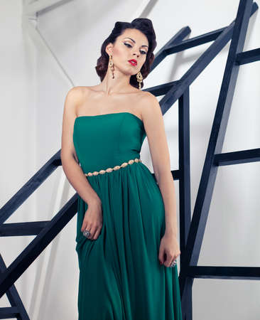 Portrait of young beautiful caucasian brunette woman in gorgeous green dress with hairdress on white backgroundの写真素材