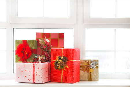 Beautiful bright Christmas gifts on windowsill over white windowの写真素材