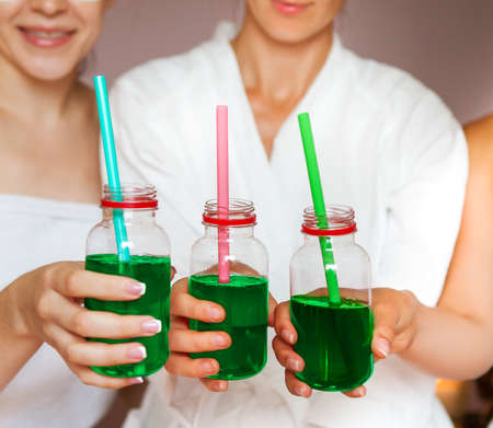 Young happy female friends drinking juice in spa and have fun. Close upの写真素材