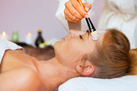 Young beautiful woman in a mask for the face of the therapeutic white mud. Spa treatmentの写真素材