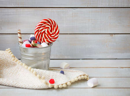 Colorful candies in a small bucket on light wooden background with copy spaceの写真素材