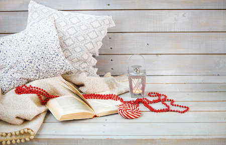 Christmas still life with lantern, candy, book and red beads on wooden backgroundの写真素材