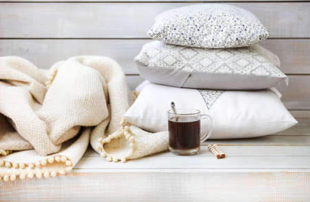 Cozy still life with coffee, pillows and plaid on the light wooden background. Close upの写真素材