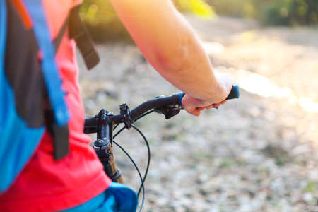 Young man with backpack on the bicycle by mountain river. Closeupの写真素材