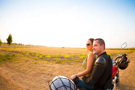Young biker couple on the country road against the sky