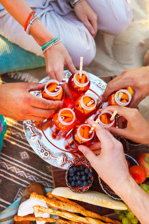 Group of friends holding drinks at the summer picnic. Close upの写真素材