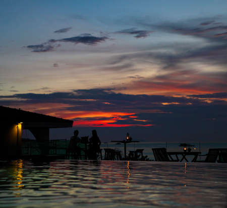 The silhouette of couple watching sunset in the beach cafeの写真素材