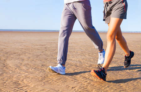 Couple jogging outside, runners training outdoors working out in nature against blue sky with sunset light. Close upの写真素材