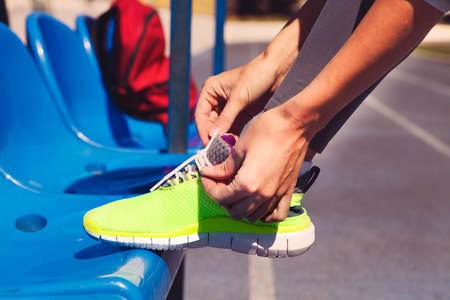Running shoes. Closeup of woman tying shoe laces. Female sport fitness runner getting ready for jogging outdoors on stadiumの写真素材