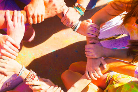 Friends putting their hands together in a sign of unity and teamwork. Holi colors festival. Friendship conceptの写真素材