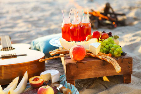 Picnic on the beach at sunset with fruits and juices in the style of bohoの写真素材