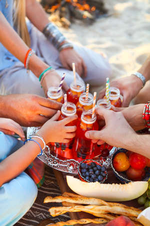 Group of friends holding drinks at the summer picnic. Close upの写真素材