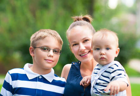 Happy mum and her children in park together. Outdoor portrait of happy family