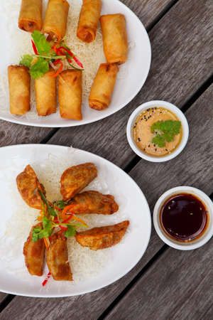 Fried Chinese traditional spring rolls and gyoza or dumpling on the wooden table