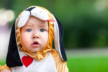 Little funny baby wearing puppy suit on green backgroundの写真素材