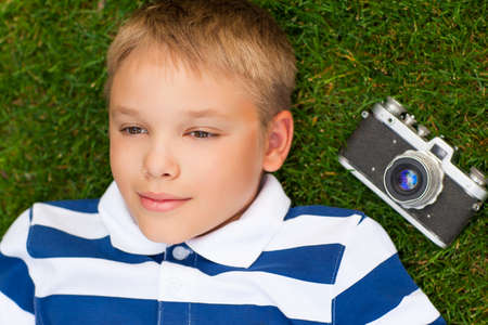 Happy smiling little boy with retro vintage camera in summer park